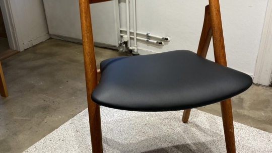 Sawbuck stol efter ompolstring med sort, elegant sæde udført i Odense på Fyn
