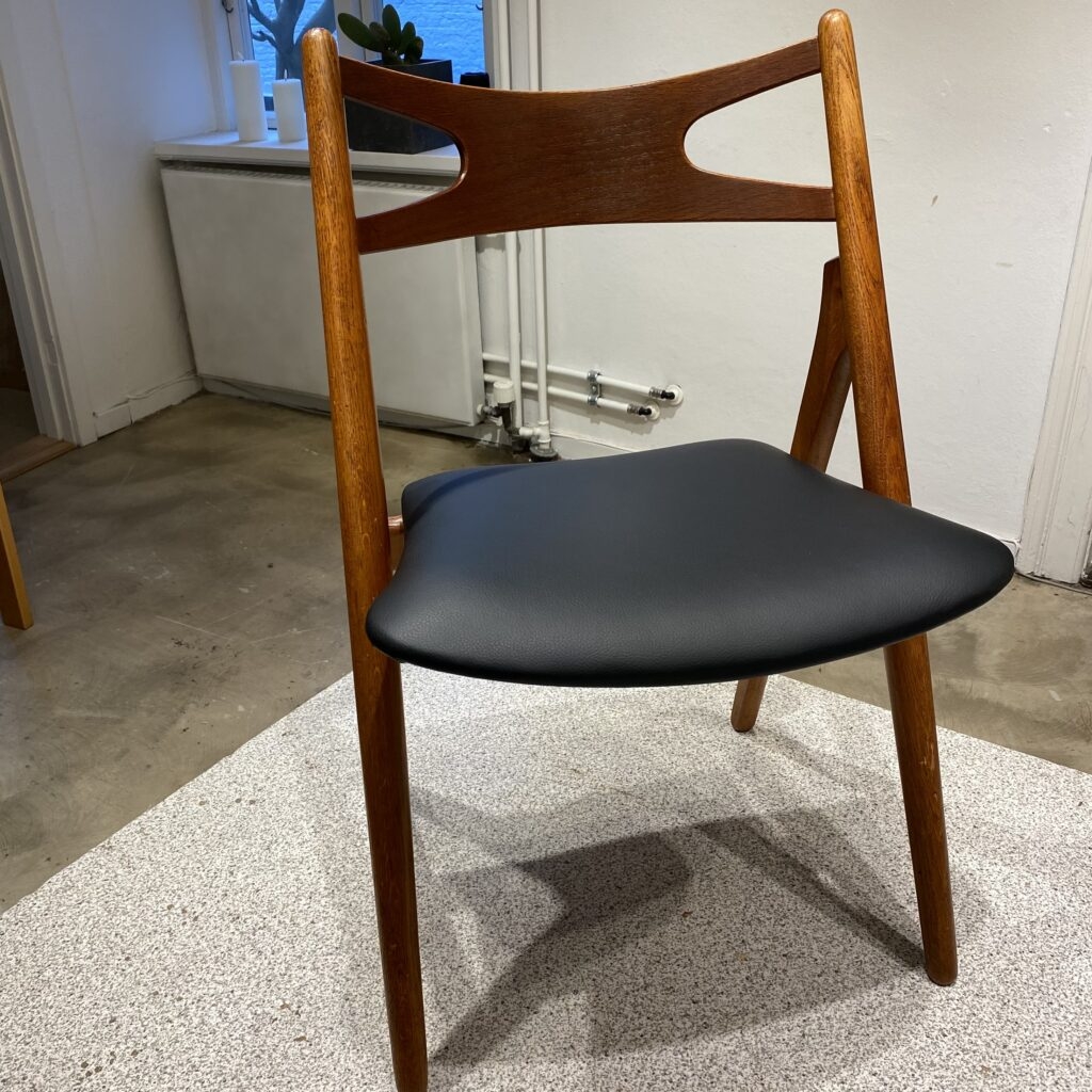 Sawbuck stol efter ompolstring med sort, elegant sæde udført i Odense på Fyn